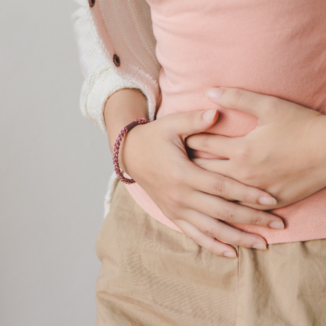 Person holding their abdomen, possibly experiencing bloating, indicating the need for gut health management.