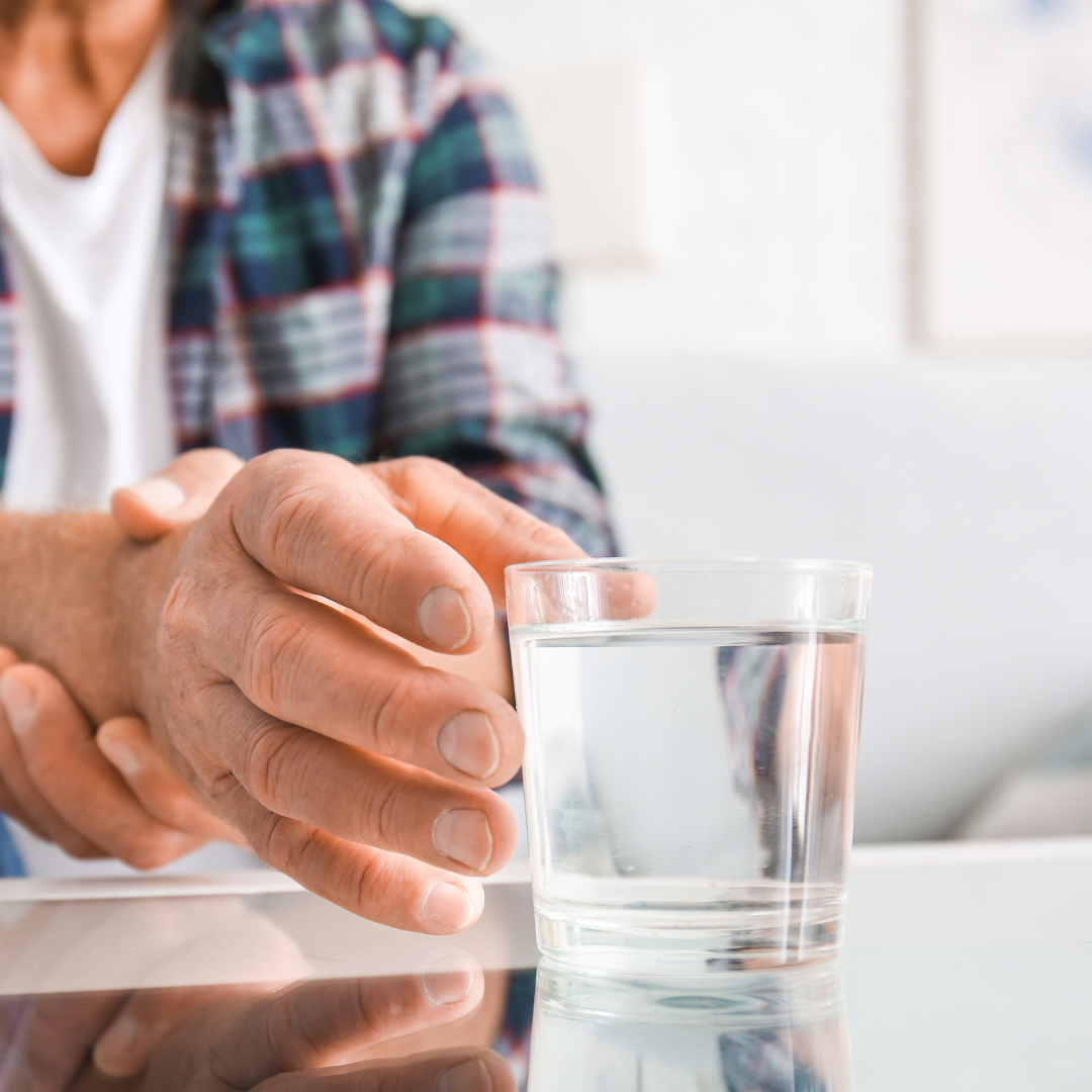 A person with Parkinson's disease reaching for a glass of water.